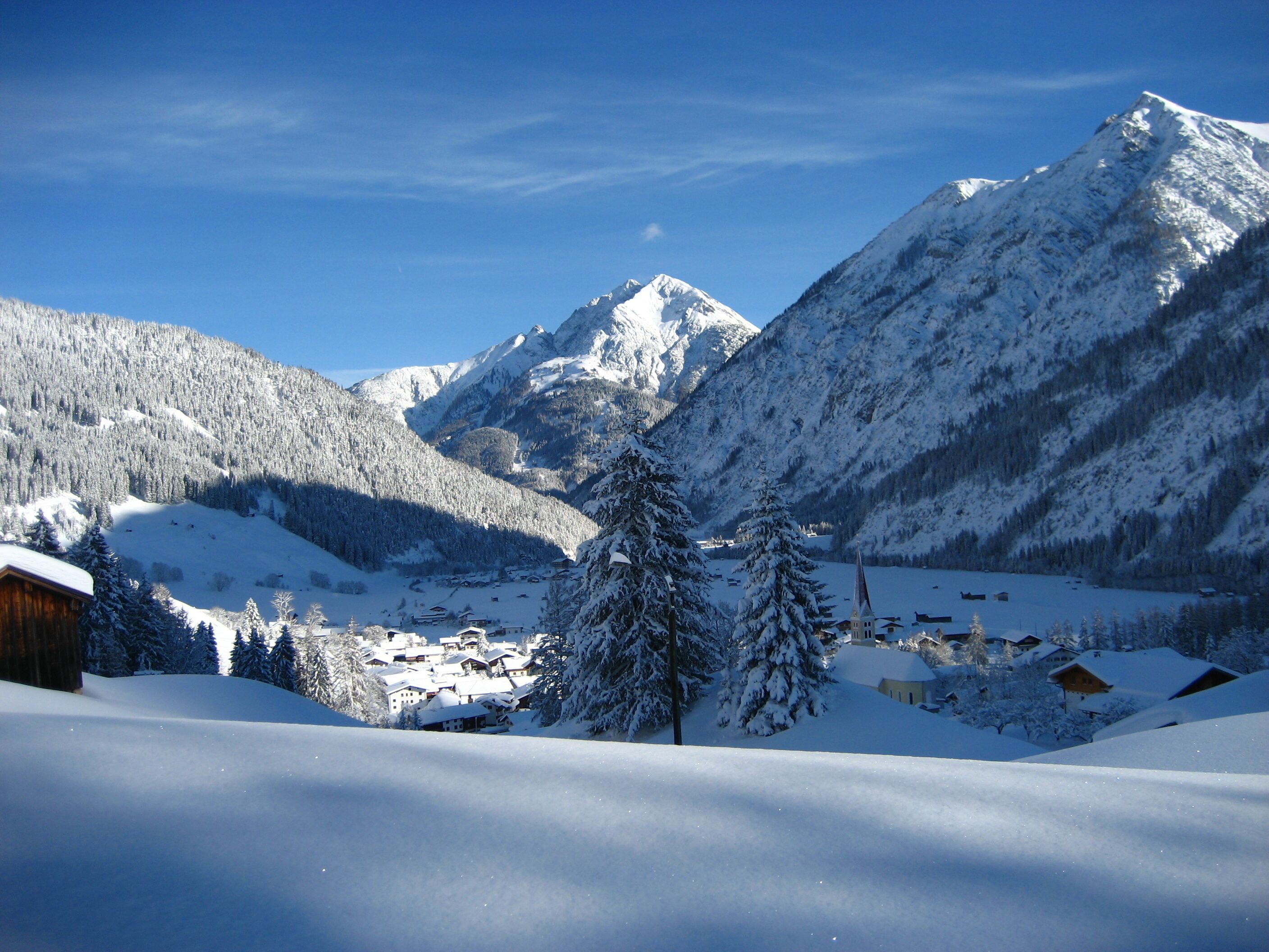 A snow-covered mountain landscape with a small village and a church.