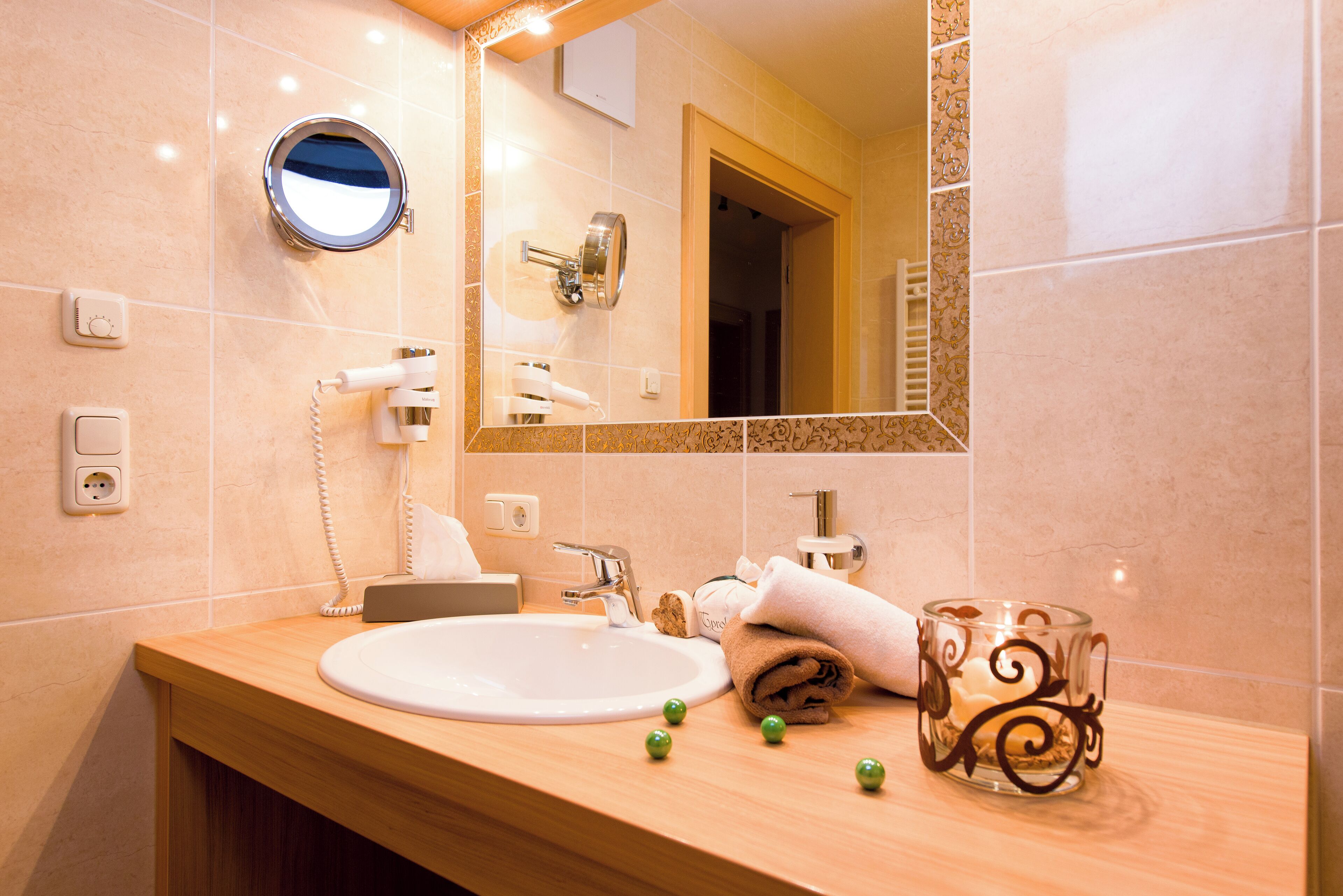 A bathroom with a sink, mirror, towel, and candle.