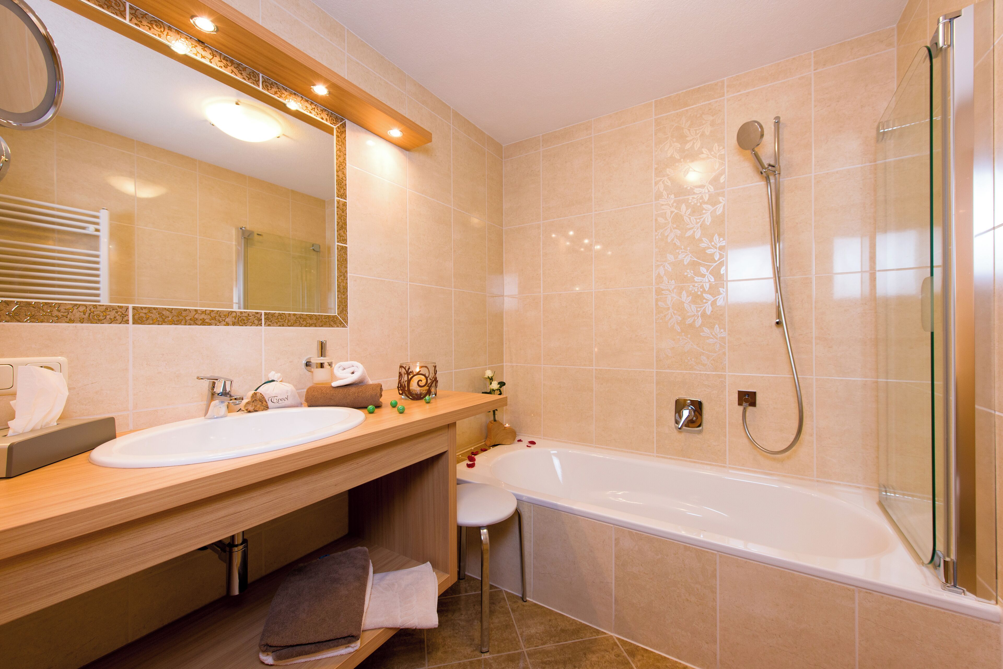 Een moderne badkamer met een grote spiegel, twee wastafels, een badkuip en een douche met glazen wanden.