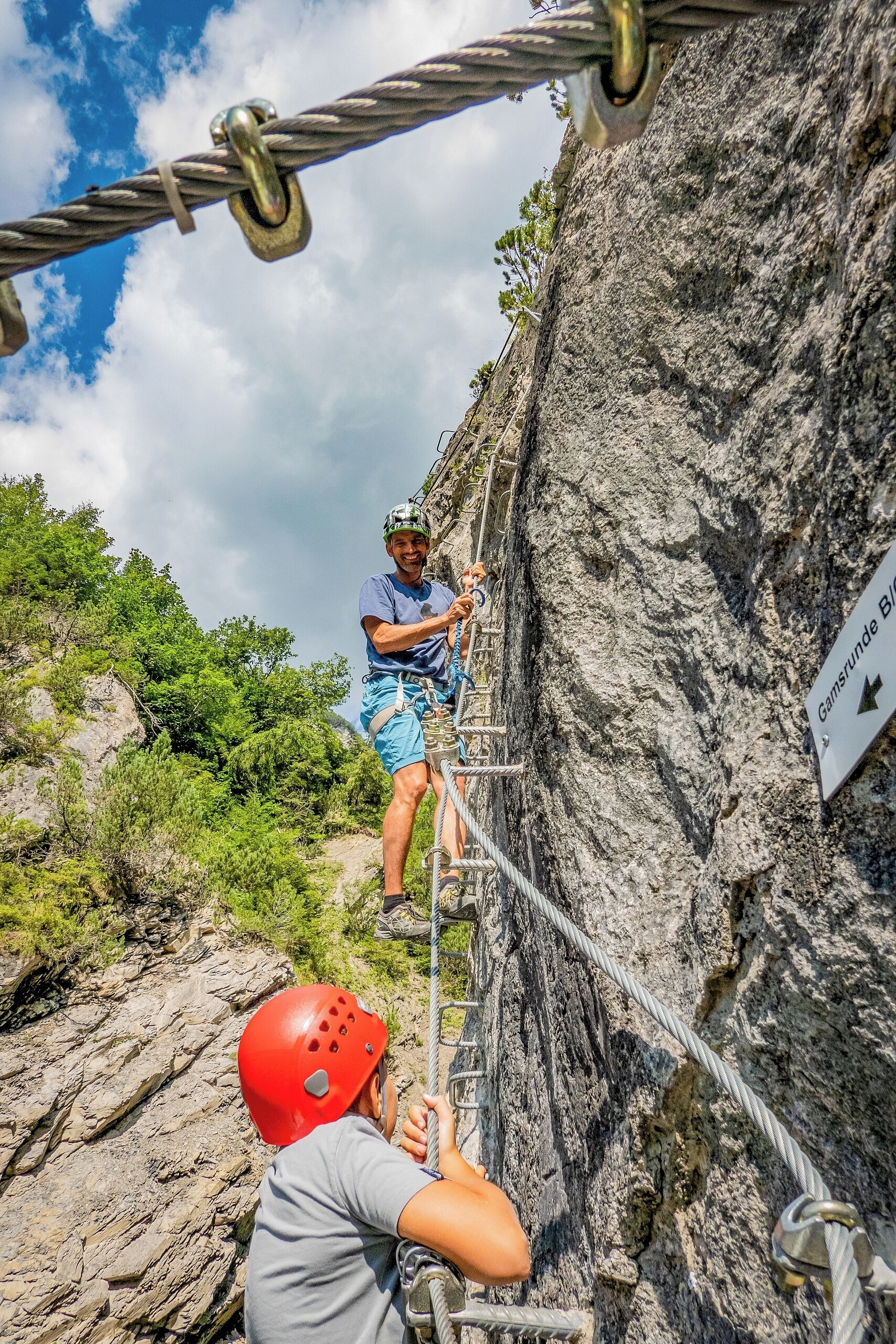 A person rappelling down a rocky cliff with a rope.