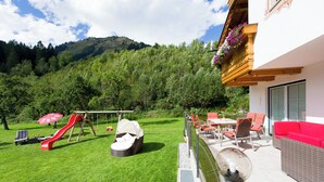 A patio with outdoor furniture, a slide, and a view of a forested hill.