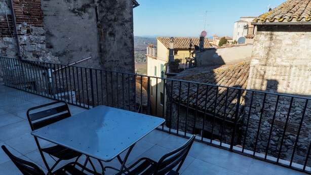 A balcony with a table and chairs, overlooking a cityscape with traditional buildings. - Todi center -Elegant apartment with Spectacular View. Unmissable Terrace! (Todi)