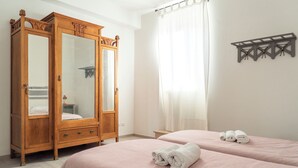 A hotel room with two beds, a wooden wardrobe, a mirror, and a shelf with towels. - Todi center -Elegant apartment with Spectacular View. Unmissable Terrace! (Todi)