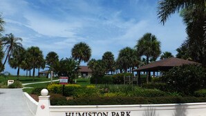 Placa indicando Humiston Park, com céu claro e palmeiras ao fundo.