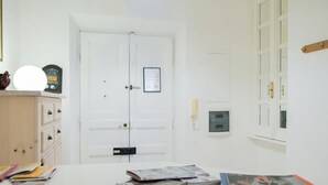 A room with a white door, a wall-mounted phone, and a bulletin board. - House of alleys (Roma)