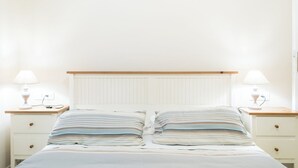 A bed with a striped pillow and a wooden headboard, flanked by two bedside tables with lamps. - House of alleys (Roma)