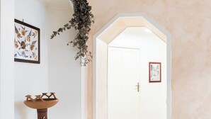 A hallway with a white door, a framed picture on the wall, and a decorative plant. - House of alleys (Roma)