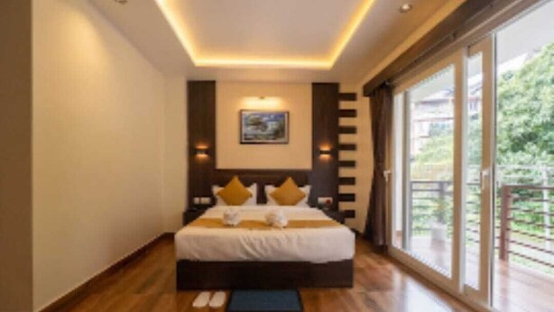 A modern bedroom with a large bed, a view of the outdoors, and a wooden floor. - Hotel Pride  (Gangtok)