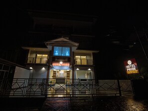 Un hôtel avec une enseigne bien visible indiquant « HÔTEL PRIDE » et une plus petite enseigne pour le « RESTAURANT HÔTEL PRIDE WATER CHOICE ».