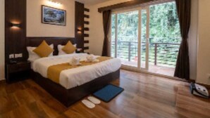 A modern bedroom with a large bed, wooden flooring, a view of greenery through the window, and a ceiling light fixture. - Hotel Pride  (Gangtok)