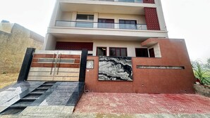 A modern multi-story building with a gated entrance, a marble-like wall feature, and a red accent wall. - Modern Comfort in the Heart of the City – Spacious Rooms & Top Amenities (agra)