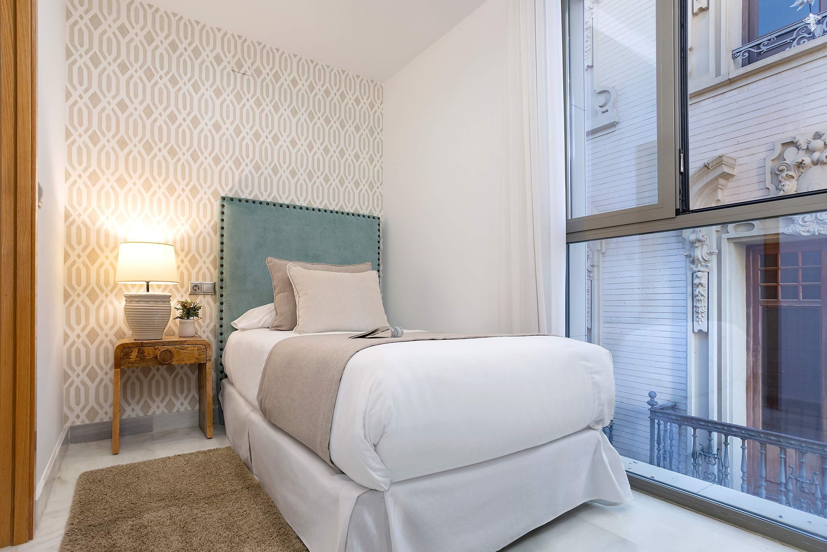 Una camera da letto con un letto, un comodino, una lampada e vista all'esterno.