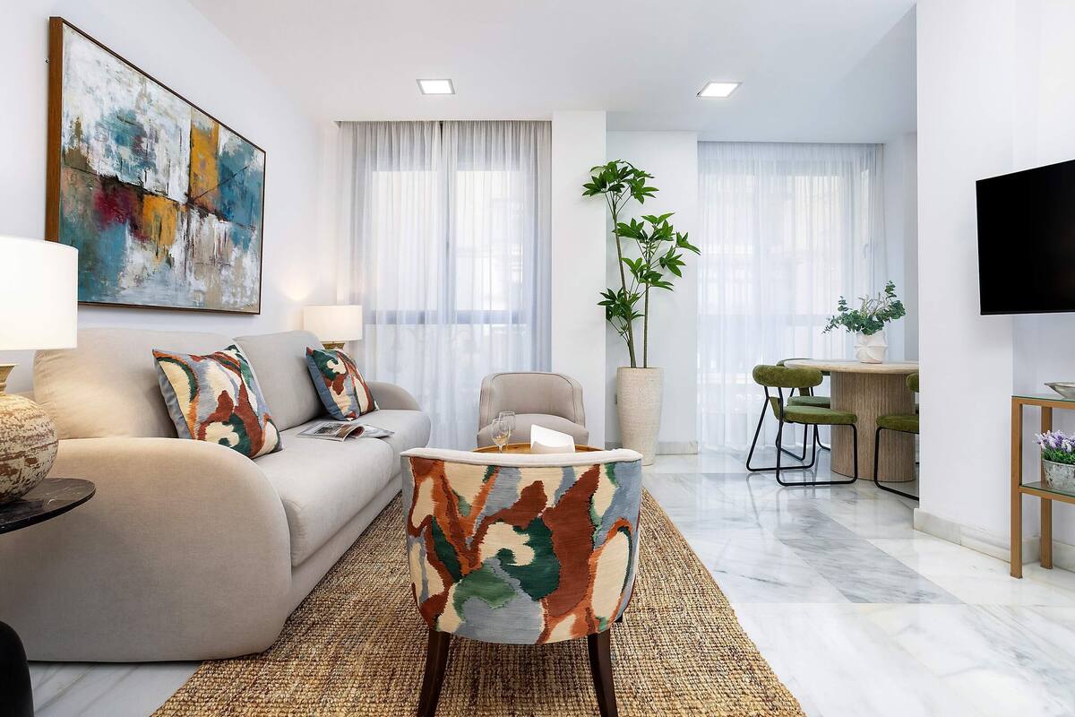 Ein modernes Wohnzimmer mit einer Couch, einem runden Couchtisch und einem Essbereich mit Stühlen.