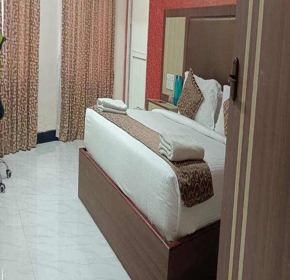 A hotel room with a large bed, a wooden headboard, a bedside table, and a mirror. - TNV Casita Inn (Yercaud)