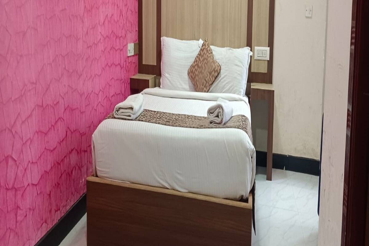 A bed with a wooden frame and a headboard, a white mattress, and a brown pillow.