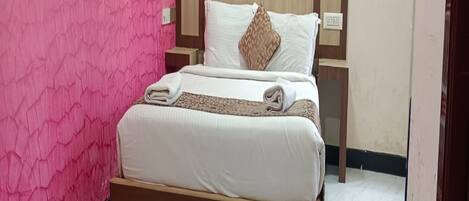 A bed with a wooden frame and a headboard, a white mattress, and a brown pillow.