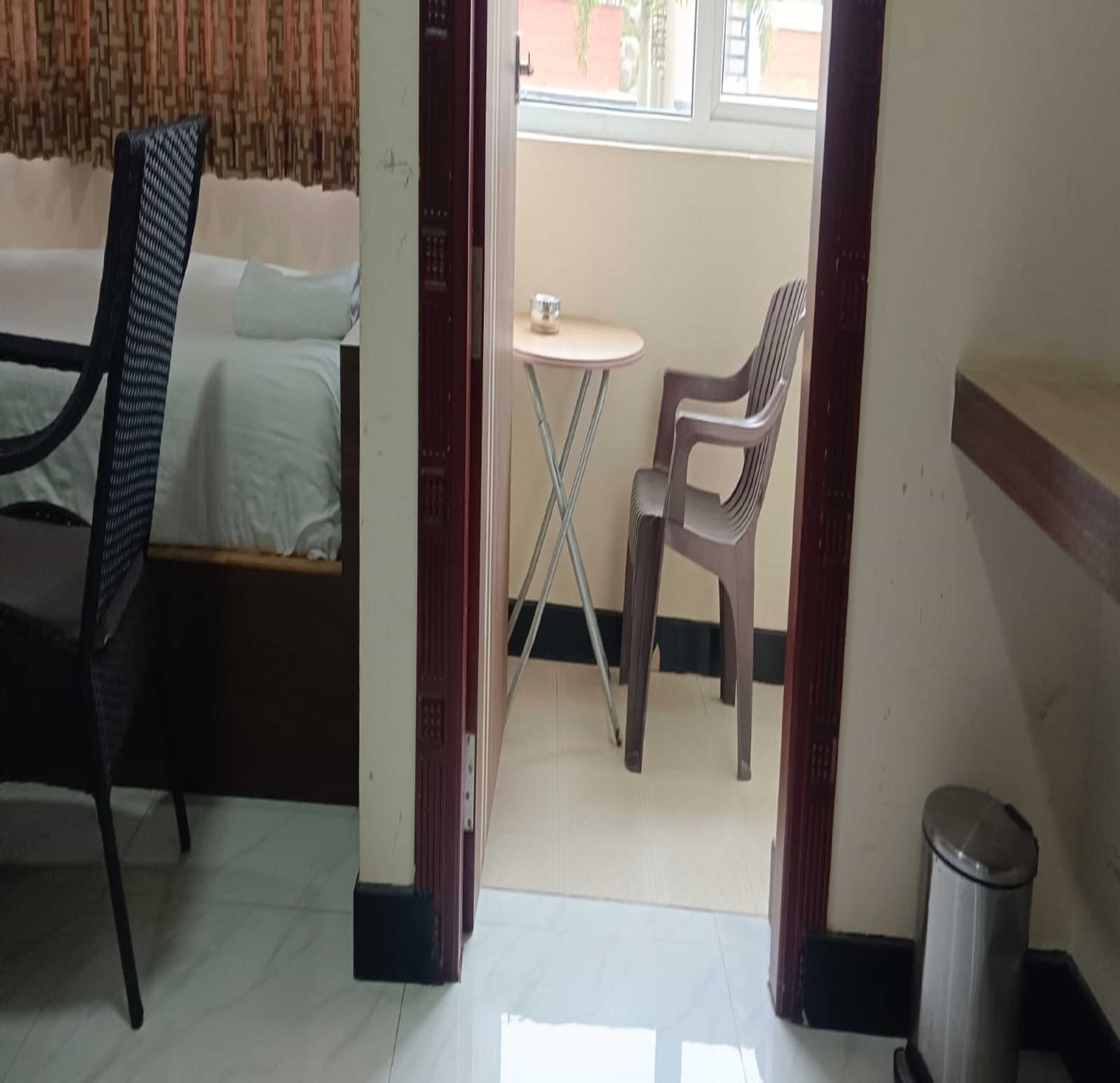 Una habitación con una cama, una silla, una mesita y un cubo de basura.