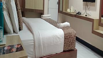 A hotel room with a bed, a desk, a mirror, a TV, and a wardrobe.