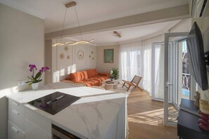 Un soggiorno moderno con isola in marmo, divano arancione e zona pranzo con tavolo e sedie.