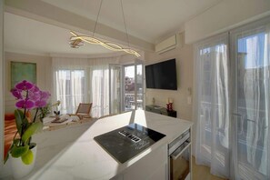 Una cucina moderna con piano cottura integrato, un'area pranzo con una sedia e un grande televisore a parete.