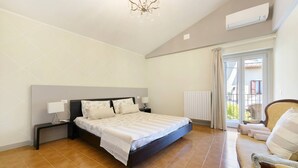 Ein Schlafzimmer mit Bett, Nachttischen, einem Sessel und Blick durch ein Fenster.