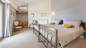Ein Schlafzimmer mit Bett, einem Sessel, einer Heizung und einem Fenster mit Vorhängen.