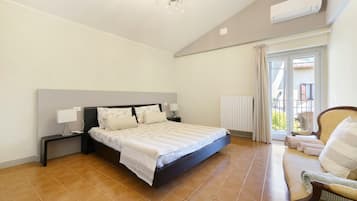 Ein Schlafzimmer mit Bett, Nachttischen, einem Sessel, einem Heizkörper und Blick durch ein Fenster.