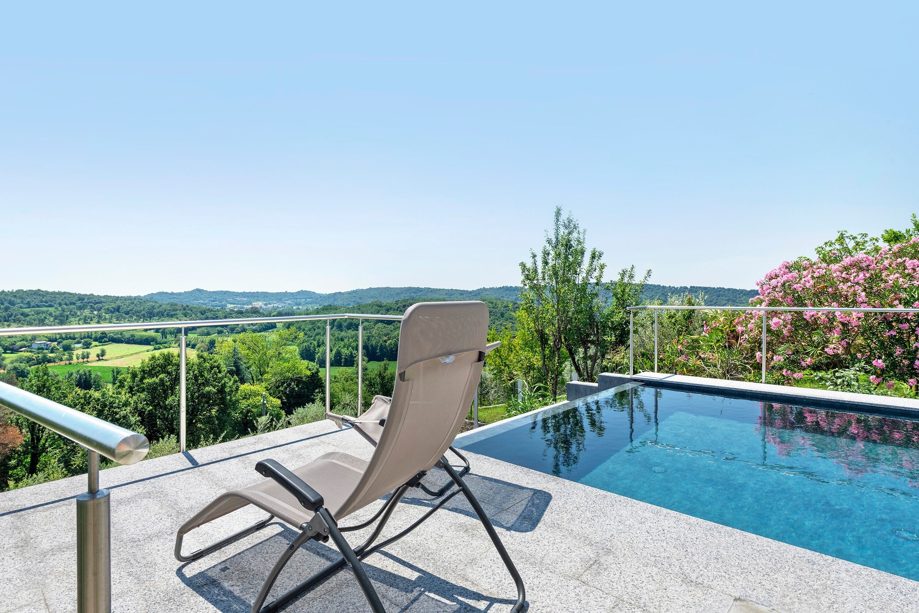 Area della piscina con una sedia, una vasca e vista sul paesaggio.