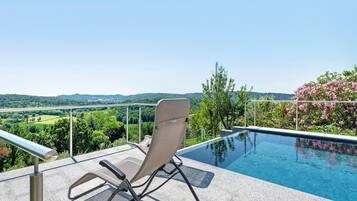Area della piscina con una sedia, una vasca e vista sul paesaggio.