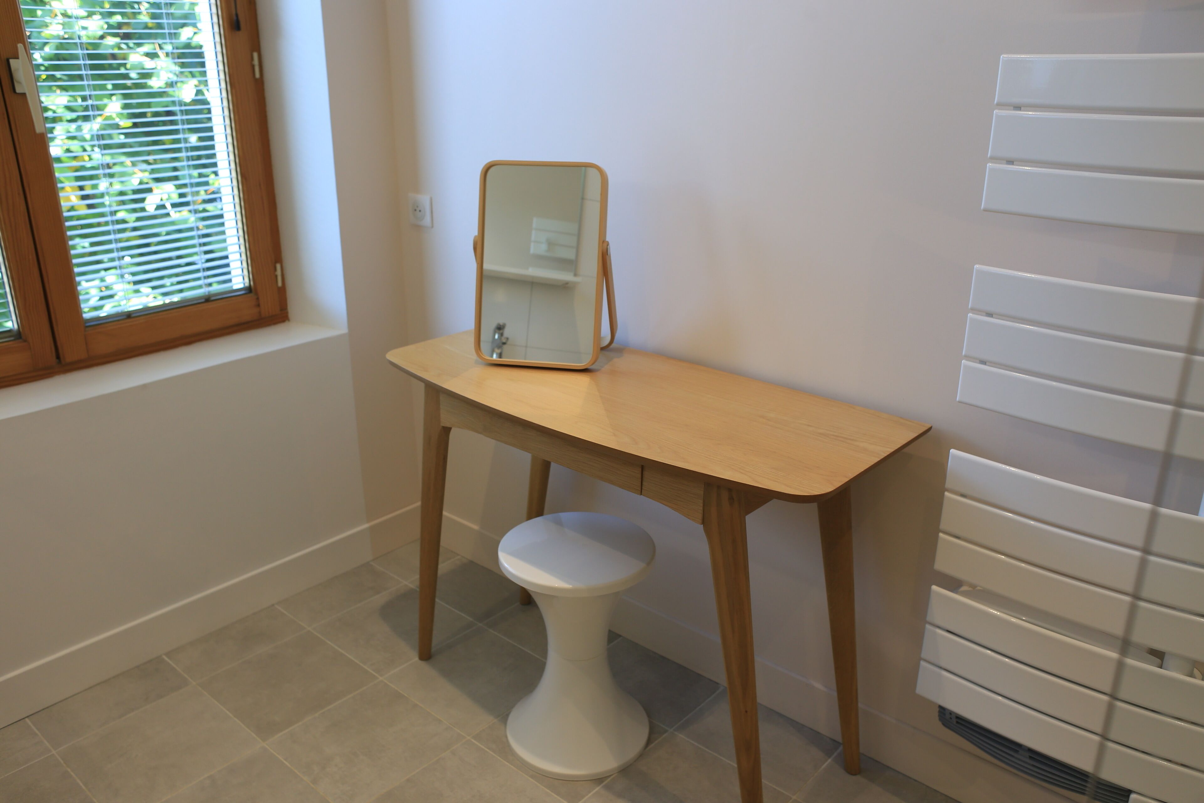A bathroom with a wooden vanity, a white pedestal sink, and a mirror.