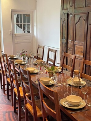 Mesa de comedor dispuesta para seis personas, con sillas de madera, una puerta blanca y un panel de pared de madera.