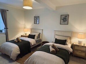Quarto com duas camas, cada uma com uma mesa de cabeceira, uma luminária e um quadro na parede.