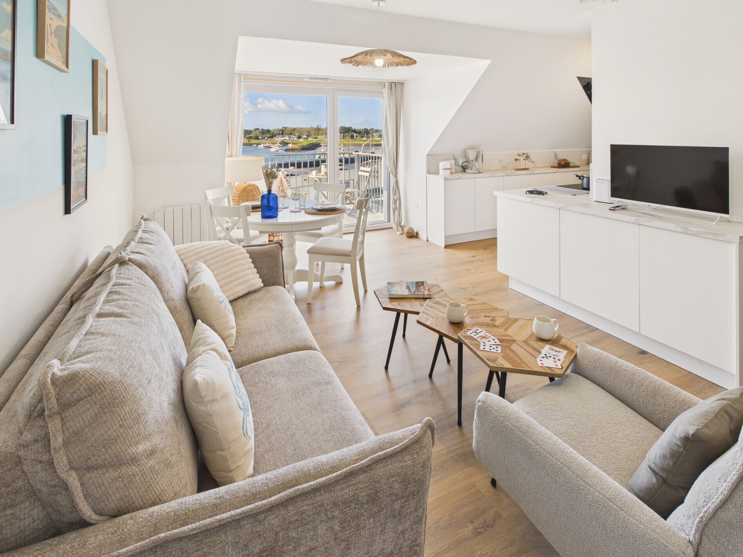 A modern living room with a sofa set, a dining table, and a kitchen area with a TV.