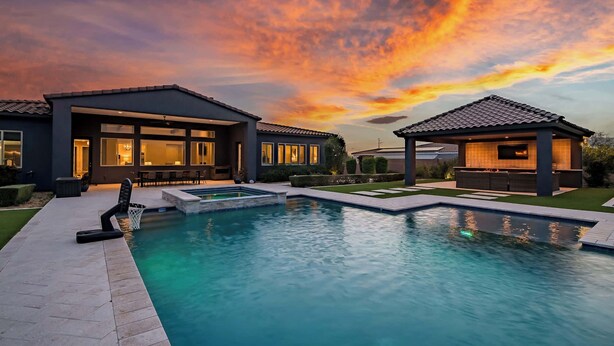 Et moderne hus med swimmingpool, store vinduer og en patio.