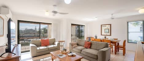 A modern living room with a sofa, coffee table, and dining area.