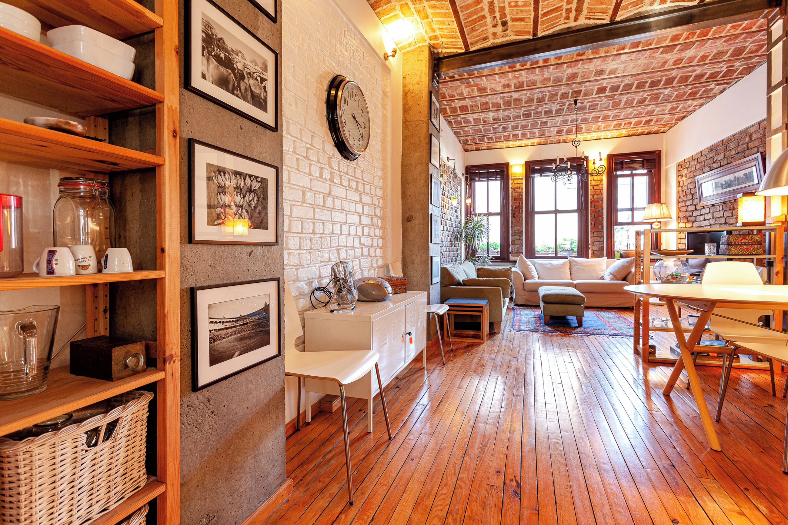 A cozy living room with wooden floors, a brick fireplace, and a white sofa.