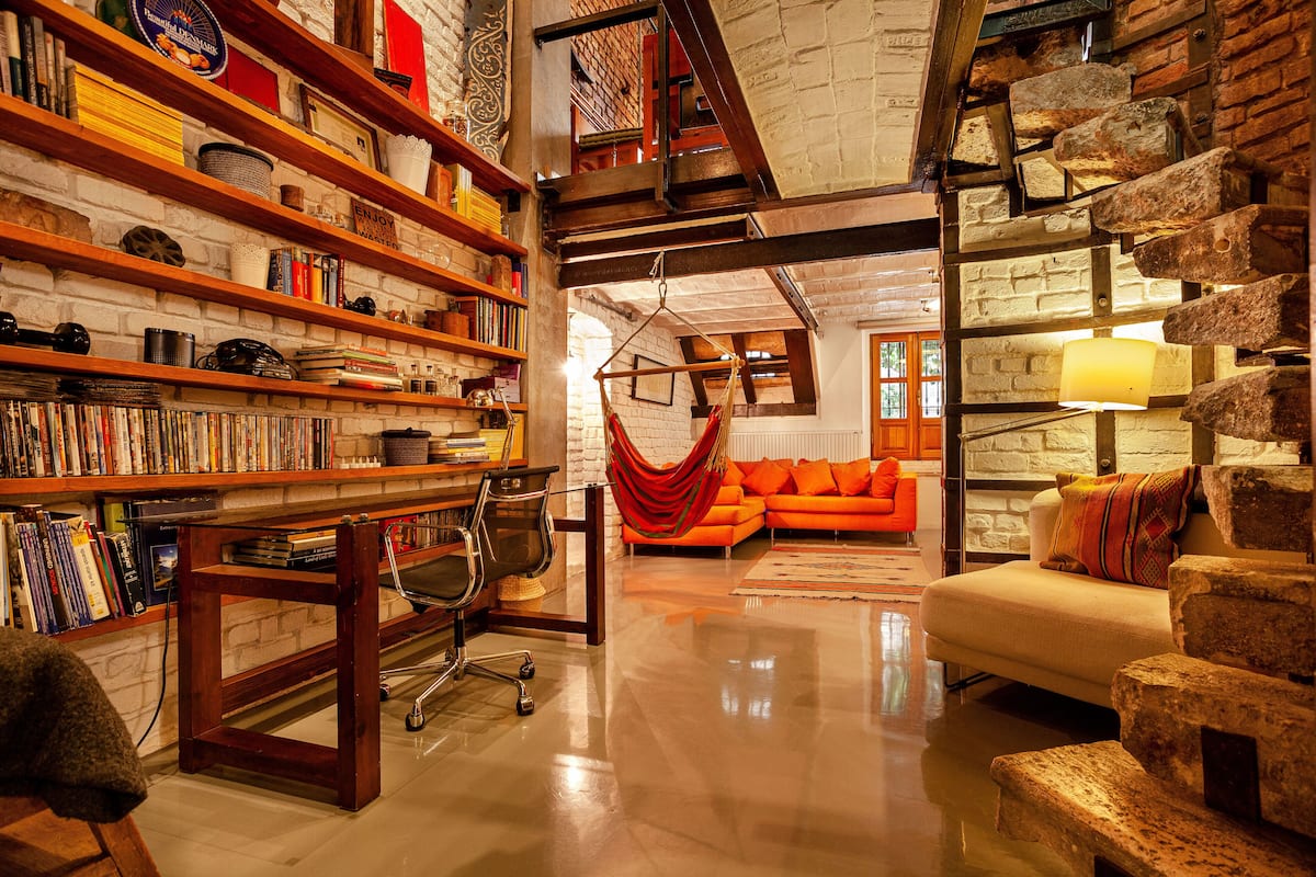A cozy living room with a fireplace, a bookshelf filled with books, and a comfortable orange sofa.