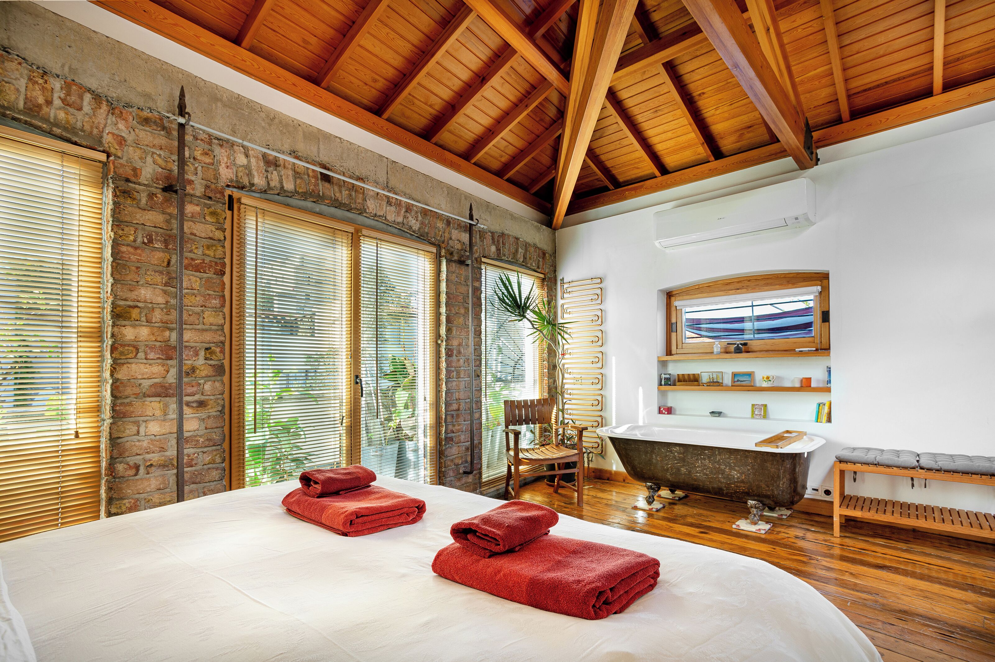 Una habitación amplia con una cama grande, una bañera y techo de madera.