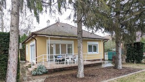 Een gelijkvloers huis met pannendak, een overdekt terras met tuinmeubilair en een verzorgde tuin met mulch en grindpaden.