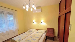 Een slaapkamer met een bed, een stoel, een kledingkast en een raam met gordijnen.