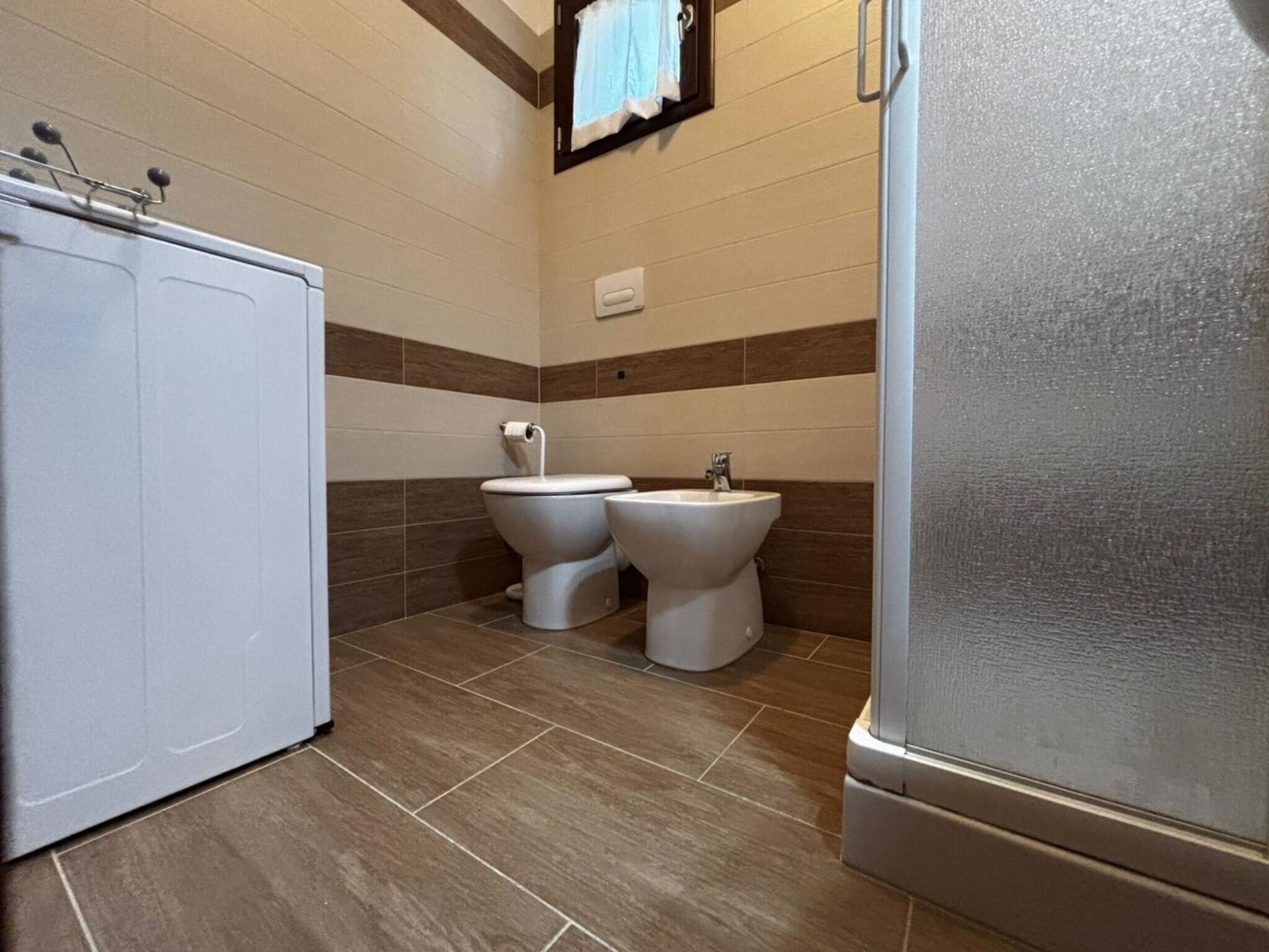 Un baño con inodoro, bidé y un armario.