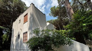 A modern building with a white facade, a wooden door, and a small window. - Cozy Apartment in the Heart of the Pinewood (Rosolina)