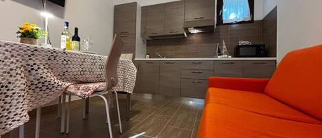 Un espace de vie compact comprenant un coin repas, une kitchenette et un canapé.