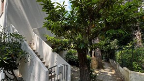 A staircase with a metal railing, surrounded by greenery and a concrete wall. - Cozy Apartment in the Heart of the Pinewood (Rosolina)