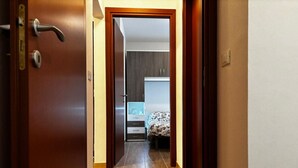 A hallway leading to a bedroom with a bed, a nightstand, and a dresser. - Cozy Apartment in the Heart of the Pinewood (Rosolina)