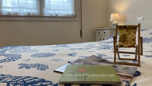 A bedroom with a bed, a chair, a nightstand, and a window with curtains. - Modern Flat Just 150 mt From the sea (Rosolina)