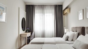 A hotel room with two beds, a desk, a chair, a mirror, and a window with curtains. - Syntagma Spotlight Residence, Bill & John Apartments & Villas (Athens)