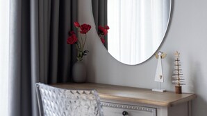 A room with a wooden dresser, a mirror, a vase with red flowers, and a small angel figurine. - Syntagma Spotlight Residence, Bill & John Apartments & Villas (Athens)