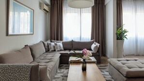 A modern living room with a sectional sofa, a coffee table, and a potted plant. - Syntagma Spotlight Residence, Bill & John Apartments & Villas (Athens)
