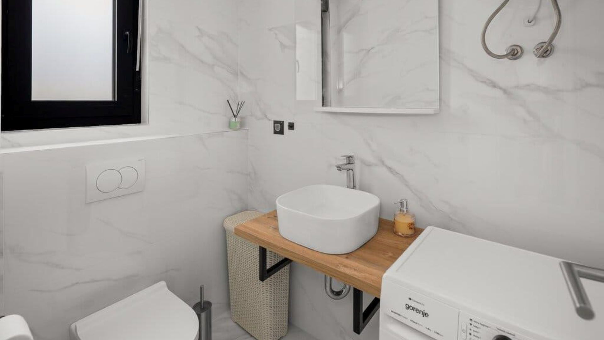 A modern bathroom with a white sink, wooden vanity, and a built-in toilet.